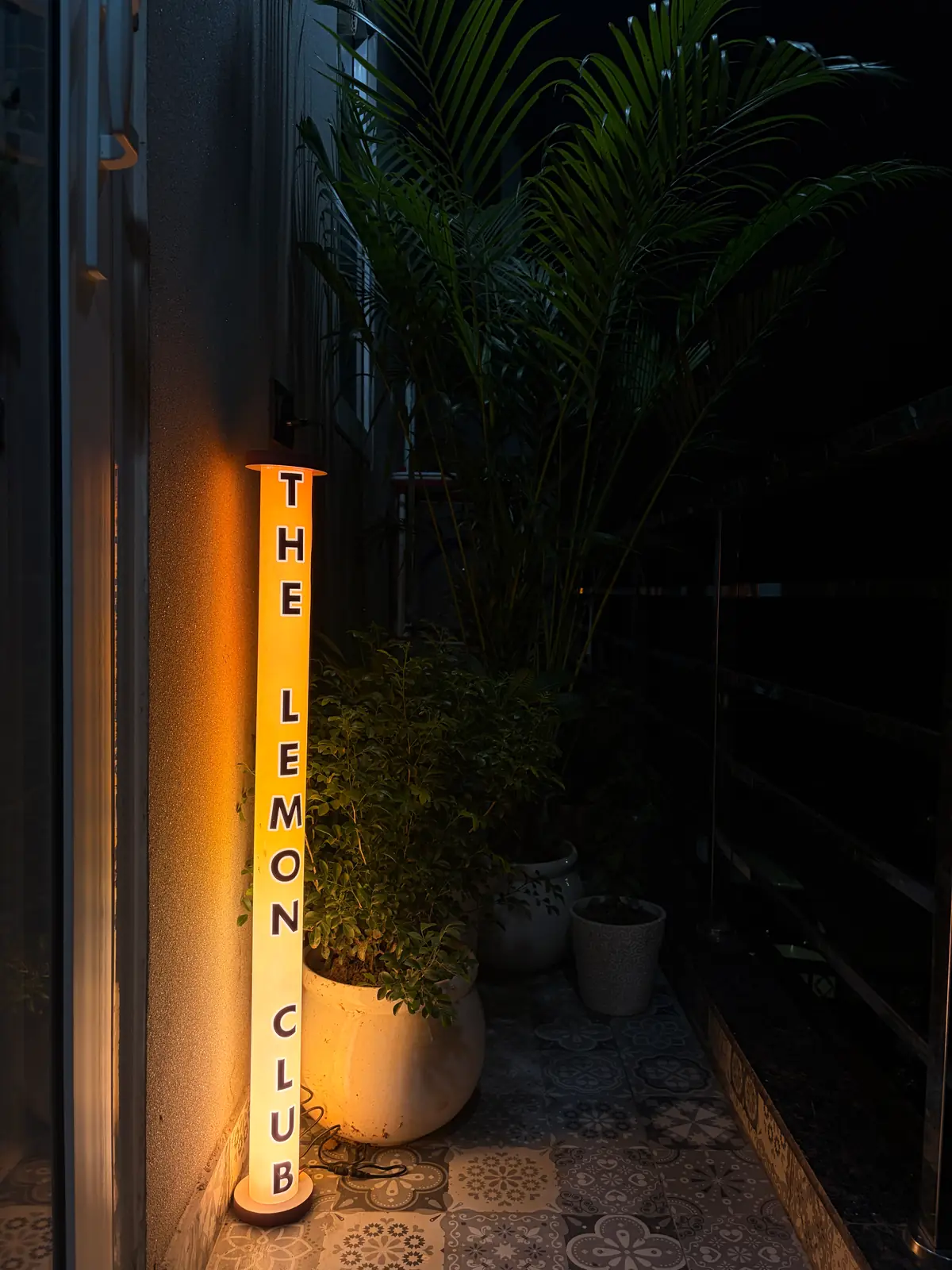 Illuminated The Lemon Club sign on the balcony at night